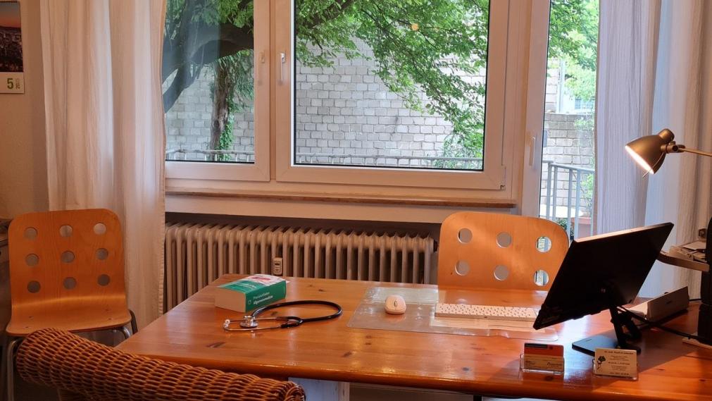 Bild des Arztzimmers mit Schreibtisch, Schreibtischlampe und Lehrbuch auf dem Schreibtisch